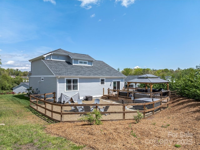 back of property featuring a gazebo, a yard, and a shingled roof