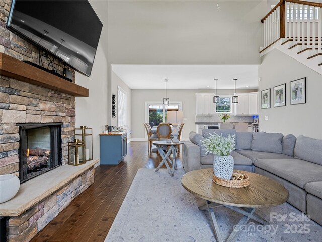 living area with baseboards, a towering ceiling, dark wood-type flooring, and a fireplace