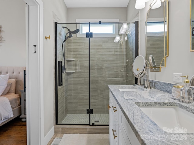 ensuite bathroom featuring a sink, double vanity, wood finished floors, a shower stall, and ensuite bath