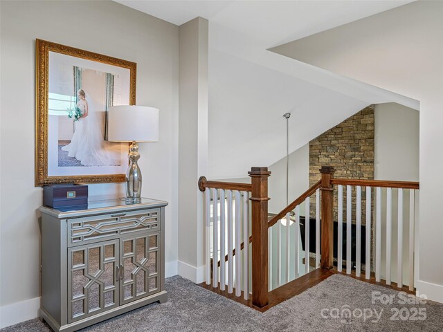 hallway featuring vaulted ceiling, baseboards, and an upstairs landing