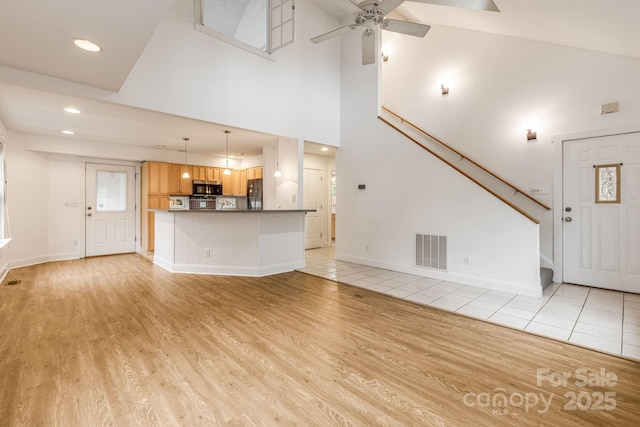 19 Castle St, Asheville, NC 28803 - unfurnished living room with light wood-type flooring, a ceiling fan, stairway, recessed lighting, and a high ceiling