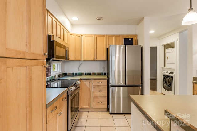19 Castle St, Asheville, NC 28803 - kitchen with stainless steel appliances, light tile patterned floors, light brown cabinets, stacked washer / dryer, and hanging light fixtures