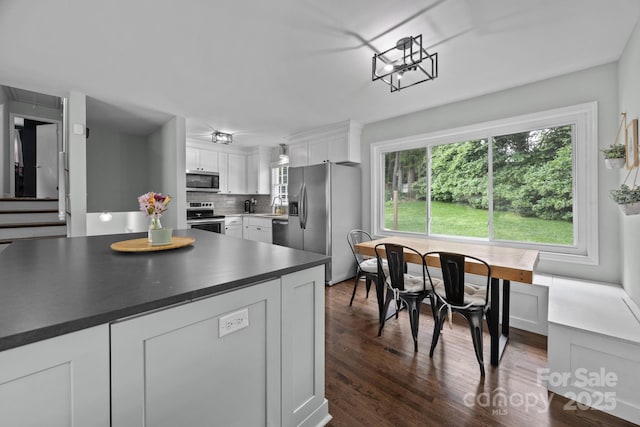 2100 Shadyview Dr, Charlotte, NC 28210 - kitchen featuring appliances with stainless steel finishes, white cabinets, dark wood-style flooring, dark countertops, and tasteful backsplash