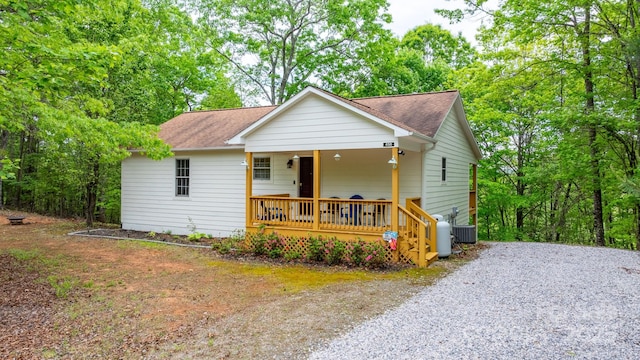 ranch-style house with a porch, a shingled roof, and gravel driveway