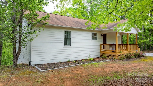 exterior space with roof with shingles and a porch