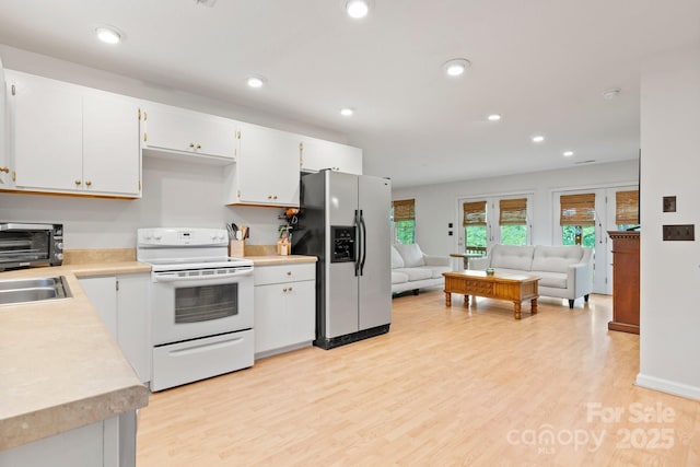 kitchen featuring stainless steel refrigerator with ice dispenser, light countertops, light wood finished floors, open floor plan, and white range with electric stovetop