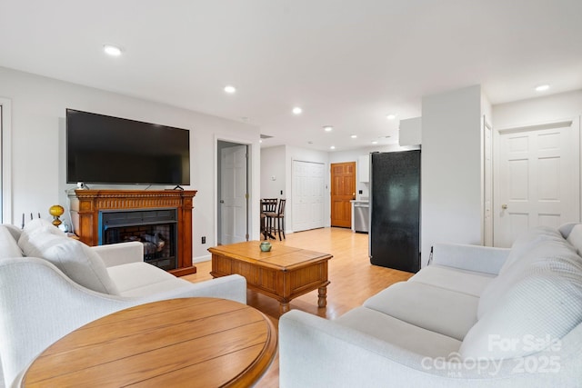 living area featuring recessed lighting, light wood finished floors, and a fireplace