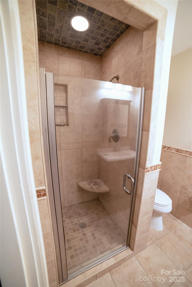 311 W Union St, Morganton, NC 28655 - bathroom featuring tile walls, toilet, tile patterned floors, a stall shower, and wainscoting