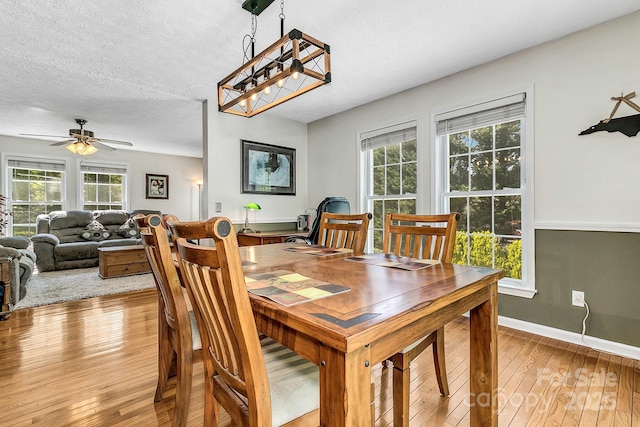 dining area with baseboards, a textured ceiling, light wood finished floors, and ceiling fan