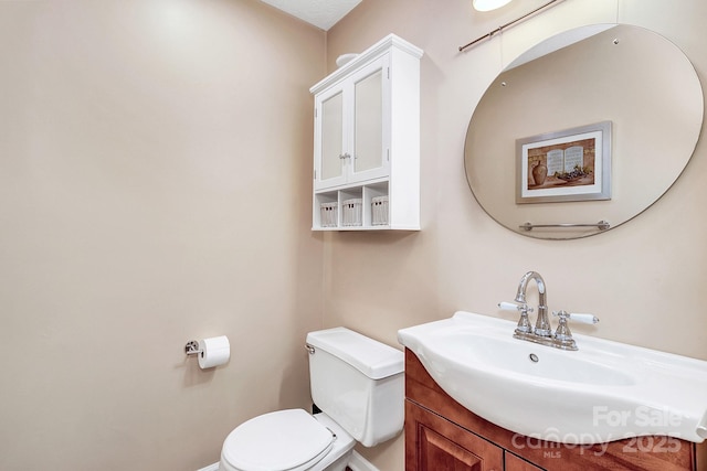 half bath with vanity, baseboards, and toilet
