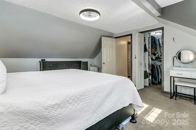 carpeted bedroom featuring a closet, lofted ceiling, baseboards, a walk in closet, and a textured ceiling