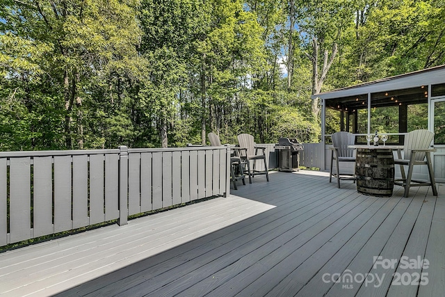 wooden deck featuring outdoor dining area and a grill