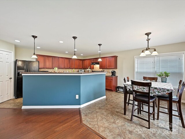 kitchen with recessed lighting, wood finished floors, decorative light fixtures, decorative backsplash, and black fridge