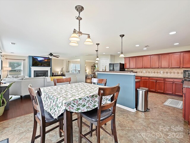 dining space featuring recessed lighting, a ceiling fan, visible vents, and a fireplace