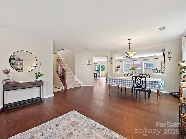 dining room featuring stairway, a wealth of natural light, wood finished floors, and visible vents