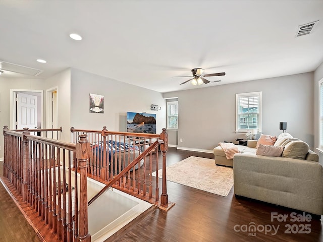 living area featuring attic access, baseboards, visible vents, ceiling fan, and dark wood-type flooring
