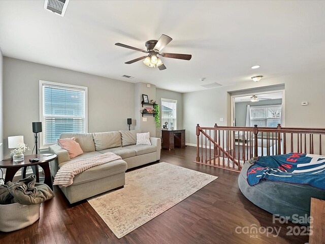 living area with visible vents, a ceiling fan, and dark wood-style flooring