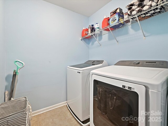clothes washing area featuring washing machine and clothes dryer, baseboards, laundry area, and light tile patterned floors