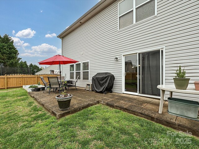 rear view of property featuring a yard, fence, and a patio area