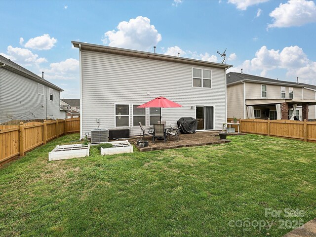 rear view of property with a fenced backyard, a lawn, a vegetable garden, and a patio area