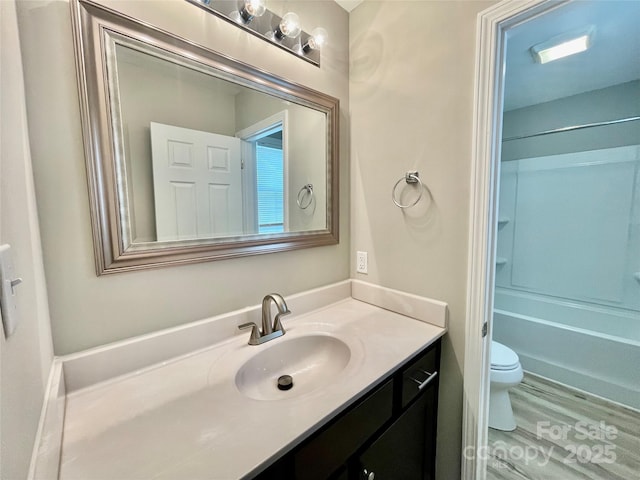 full bath featuring toilet, vanity, wood finished floors, and bathing tub / shower combination