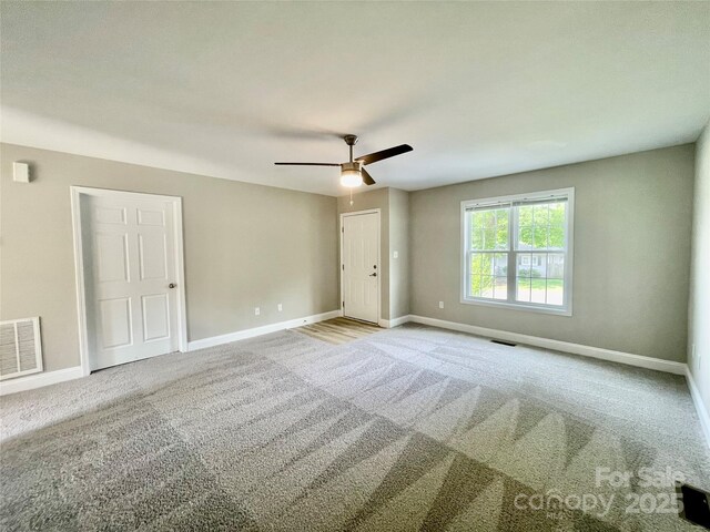 carpeted spare room with a ceiling fan and baseboards