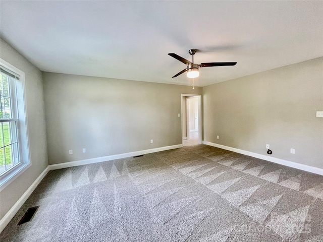 empty room with plenty of natural light, carpet flooring, ceiling fan, and baseboards