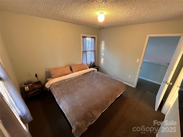 bedroom with dark carpet, a textured ceiling, and baseboards