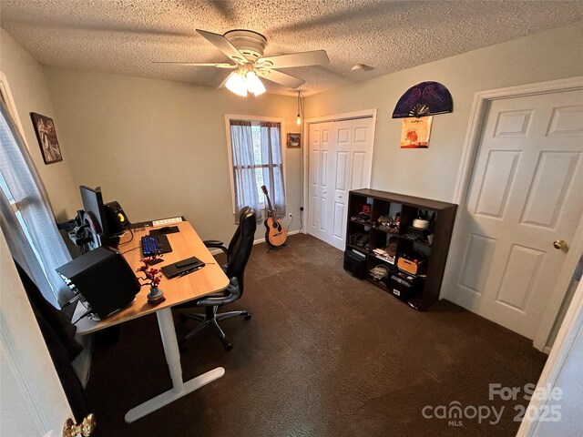 office area featuring dark colored carpet, a textured ceiling, and ceiling fan