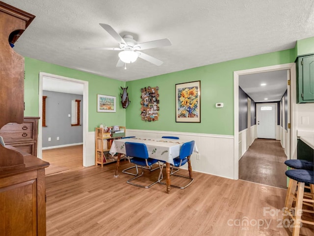 125 Snug Harbor Cir, Lake Lure, NC 28746 - dining room featuring a ceiling fan, light wood finished floors, wainscoting, and a textured ceiling