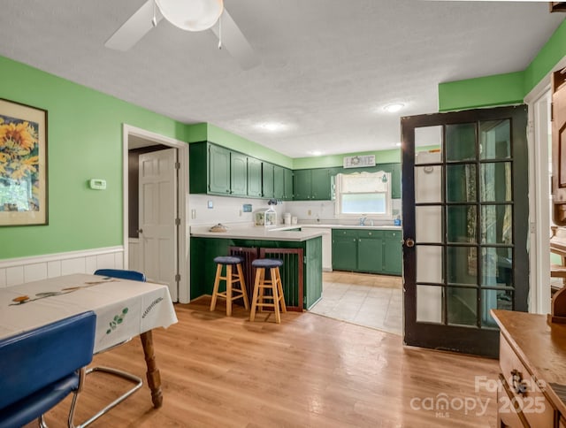 125 Snug Harbor Cir, Lake Lure, NC 28746 - kitchen with a ceiling fan, green cabinets, a sink, a kitchen bar, and a peninsula