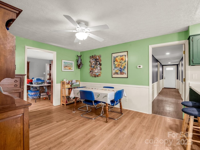 125 Snug Harbor Cir, Lake Lure, NC 28746 - dining area with a textured ceiling, light wood-style flooring, ceiling fan, and wainscoting