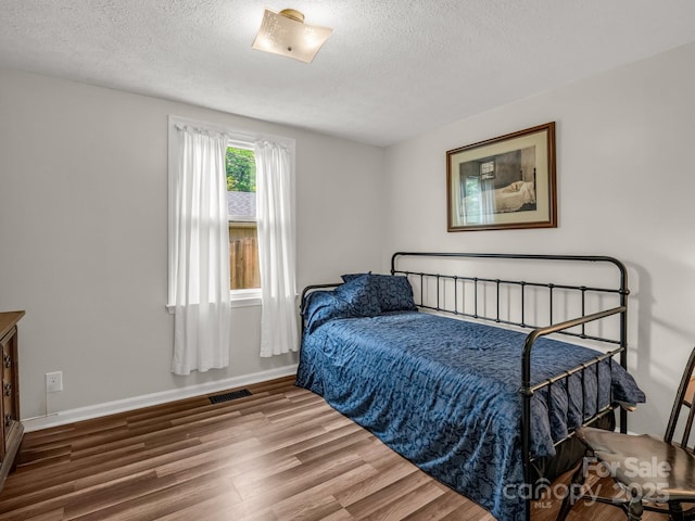 125 Snug Harbor Cir, Lake Lure, NC 28746 - bedroom featuring baseboards, visible vents, a textured ceiling, and wood finished floors