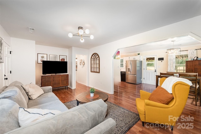 living room featuring baseboards, a notable chandelier, and dark wood-type flooring