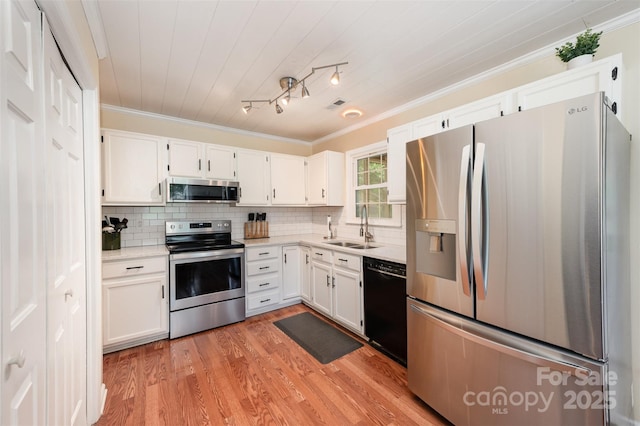 kitchen featuring white cabinets, stainless steel appliances, ornamental molding, and a sink