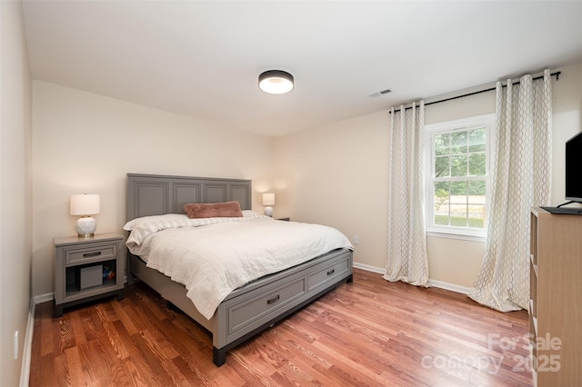 bedroom featuring visible vents, baseboards, and wood finished floors
