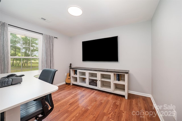 office space featuring baseboards, light wood-style flooring, and visible vents