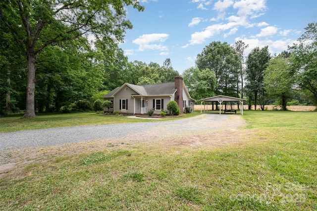 view of front of home featuring a detached carport, a chimney, gravel driveway, and a front lawn