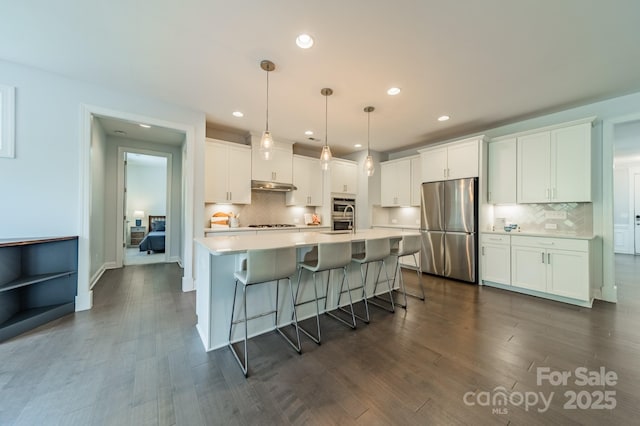 kitchen with light countertops, under cabinet range hood, tasteful backsplash, and stainless steel appliances