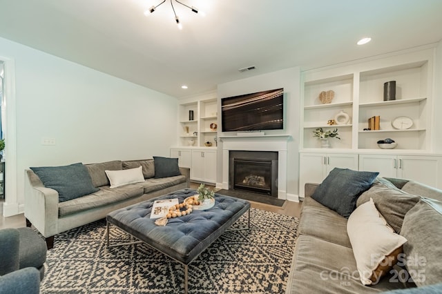 living room with visible vents, a glass covered fireplace, wood finished floors, baseboards, and recessed lighting