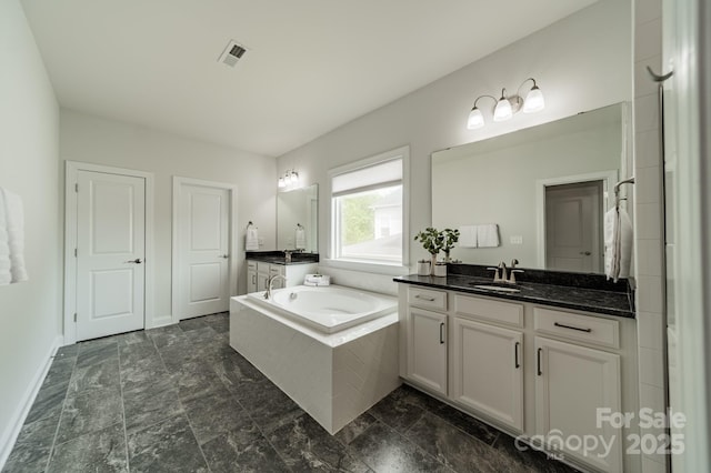 bathroom with vanity, baseboards, stone finish flooring, visible vents, and a bath