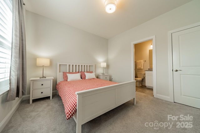 bedroom featuring baseboards, ensuite bath, and light carpet