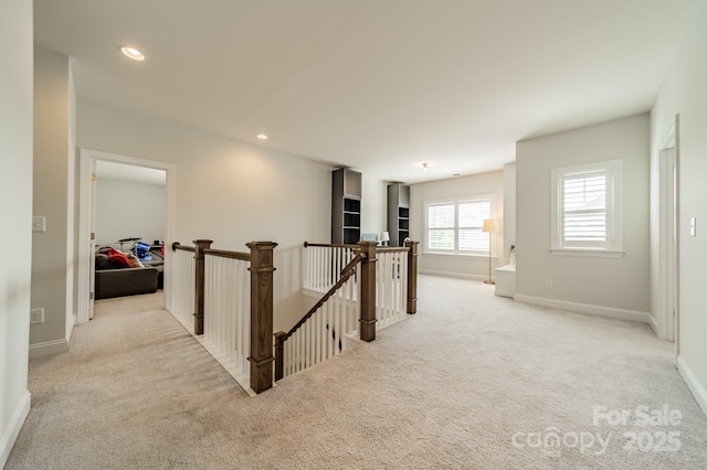 hallway with baseboards, carpet flooring, and an upstairs landing