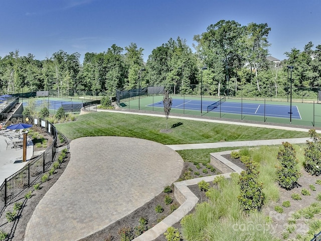 view of tennis court featuring a yard and fence