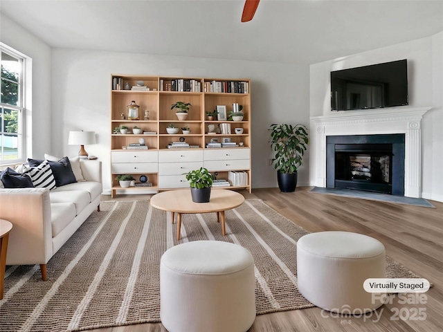 living room featuring a fireplace with flush hearth and wood finished floors