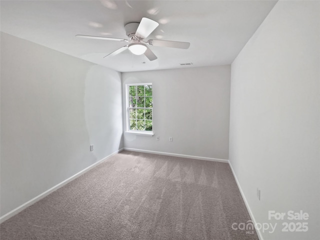 carpeted spare room with visible vents, a ceiling fan, and baseboards