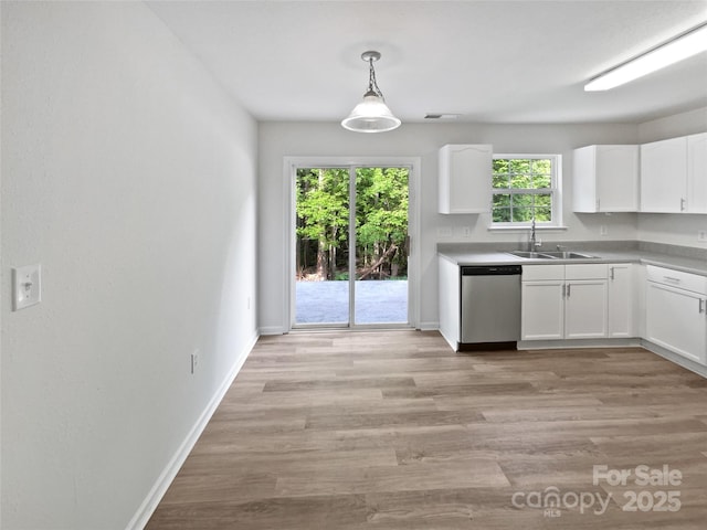 kitchen with white cabinets, stainless steel dishwasher, a sink, light wood-type flooring, and baseboards