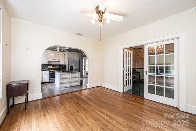 625 2nd St NE, Hickory, NC 28601 - unfurnished living room with a ceiling fan, arched walkways, wood-type flooring, crown molding, and baseboards