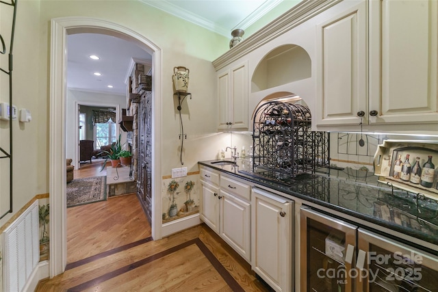 3400 Baucom Manor Rd, Monroe, NC 28110 - bar area with beverage cooler, crown molding, a sink, arched walkways, and light wood-style flooring