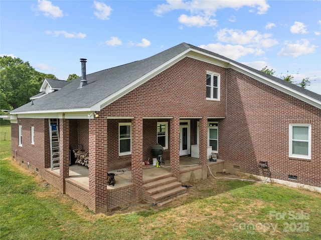 back of house featuring crawl space, brick siding, a patio area, and a yard